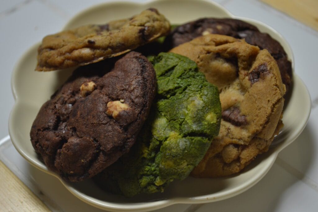 Prato com cookies de baunilha com gotas de chocolate, chocolate com trio de chocolate e matcha com chocolate branco